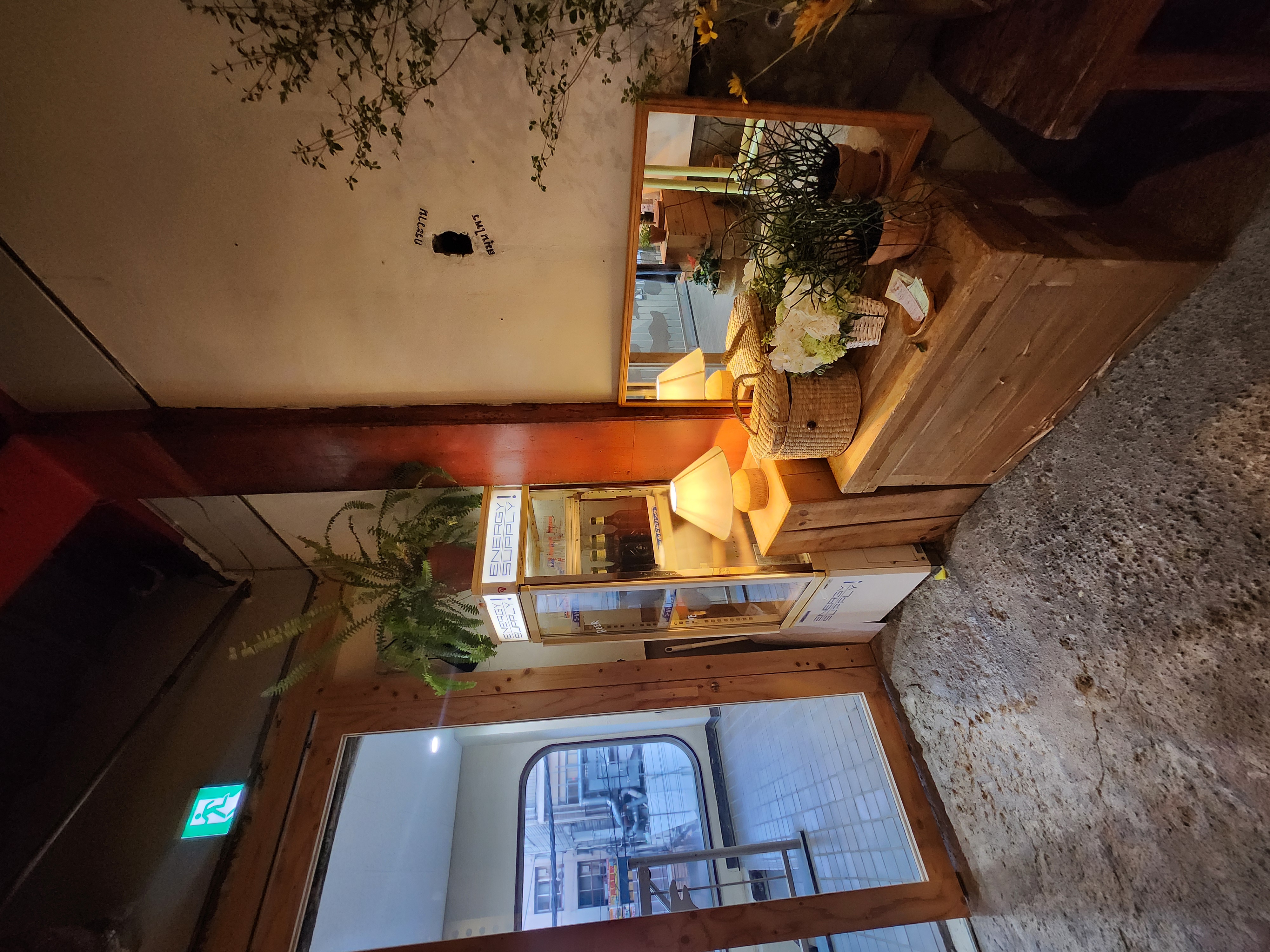 Warm interior corner with lamps, plants, baskets and a vintage drinks fridge