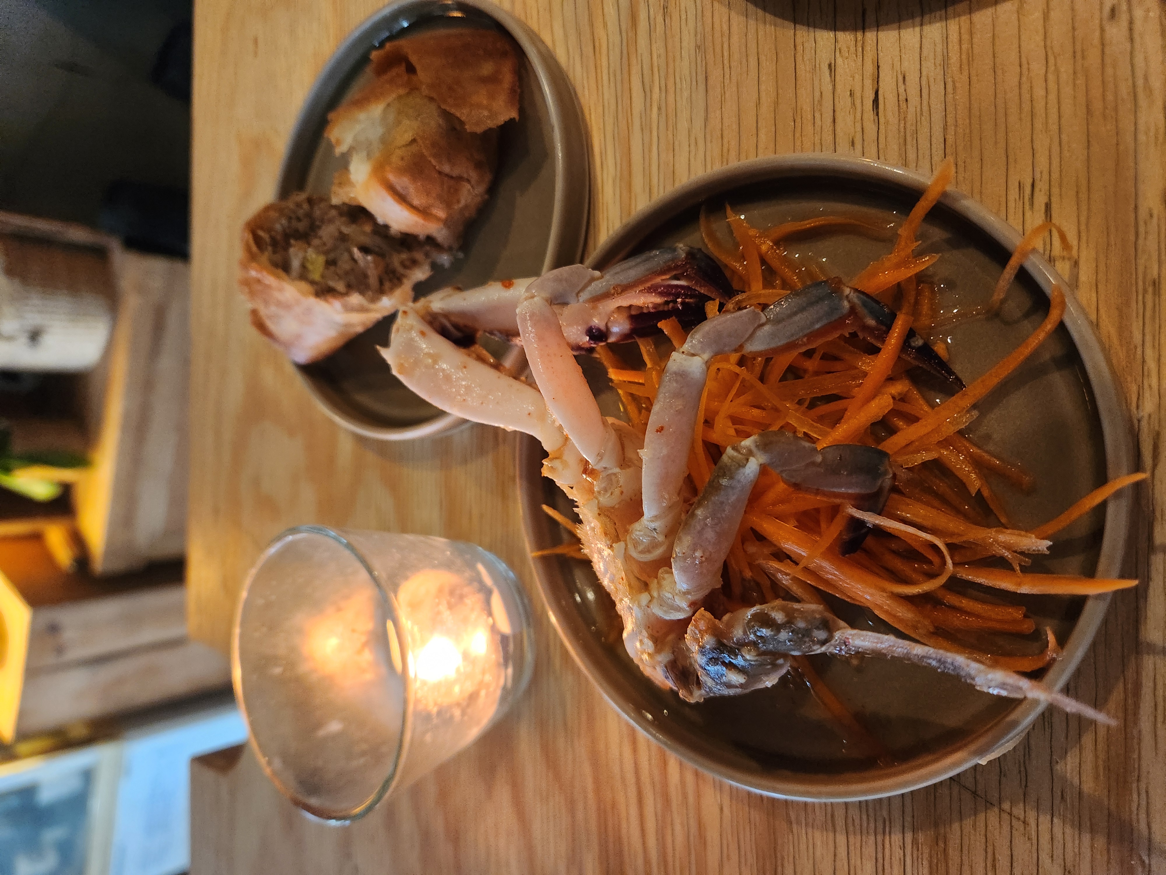 Raw blue prawns over shredded carrot beside a crisp fried roll