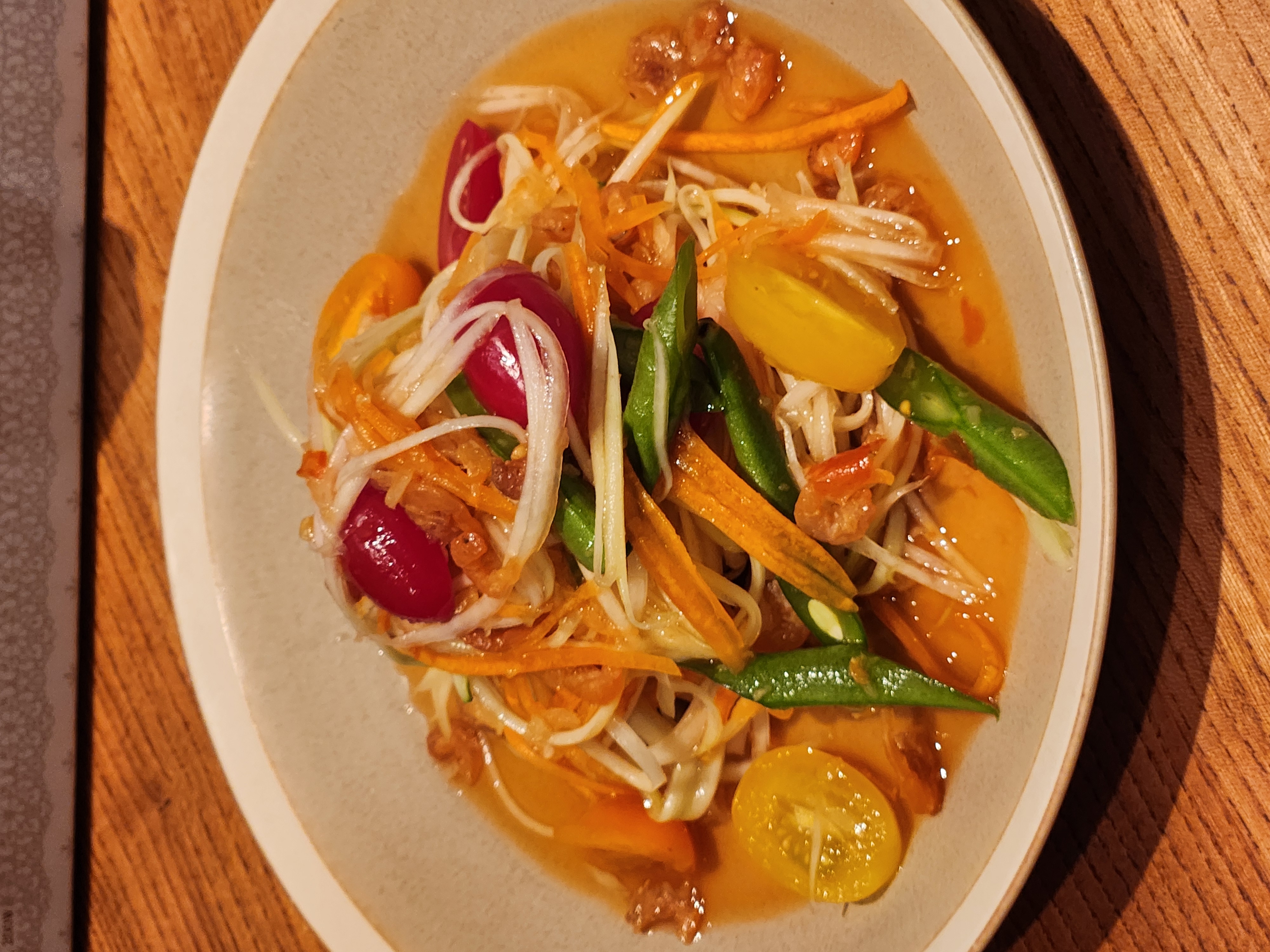 Vibrant green papaya som tam with heirloom tomatoes and long beans