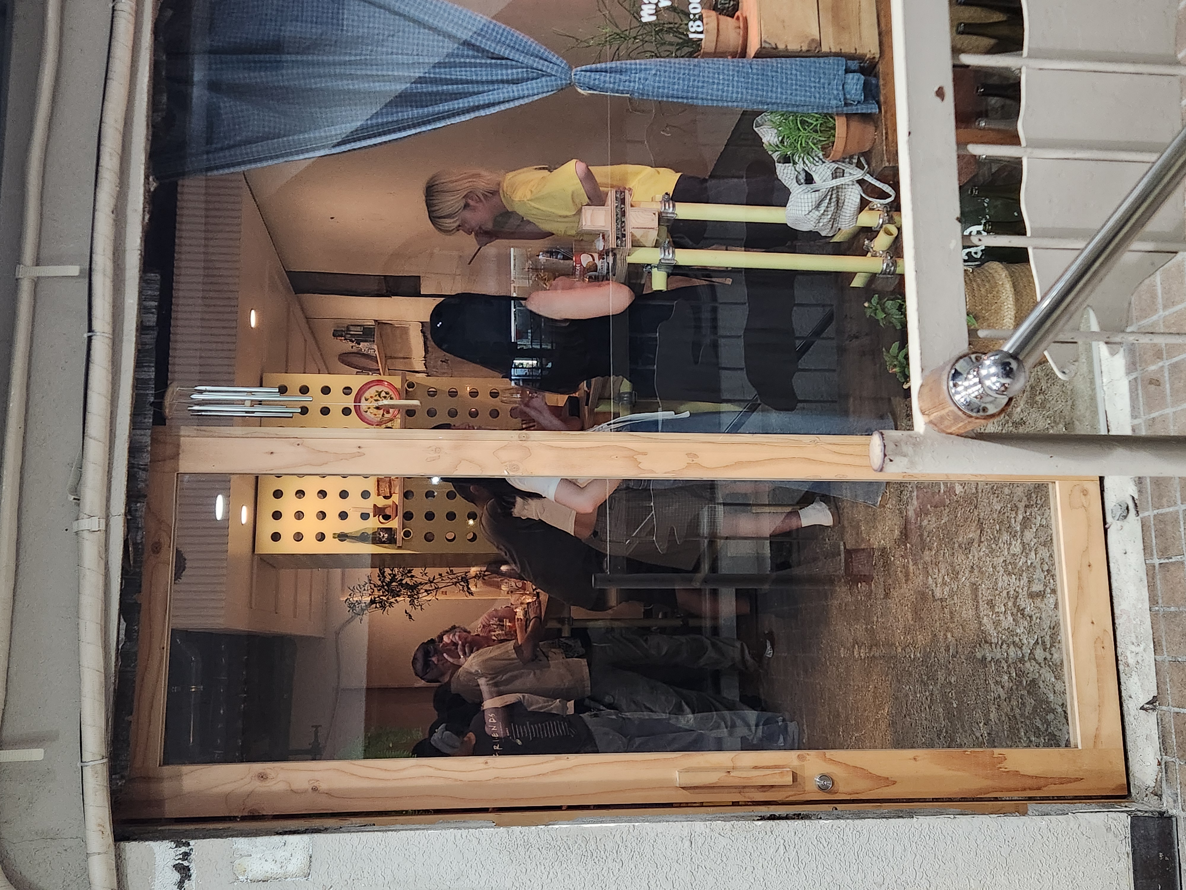 View through the window from the street, guests standing and drinking inside